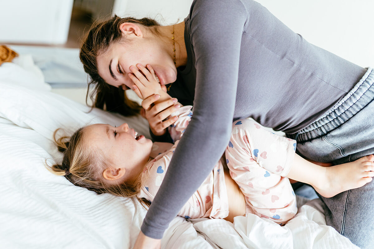 Mother and 4-year-old daughter enjoy playful morning on bed